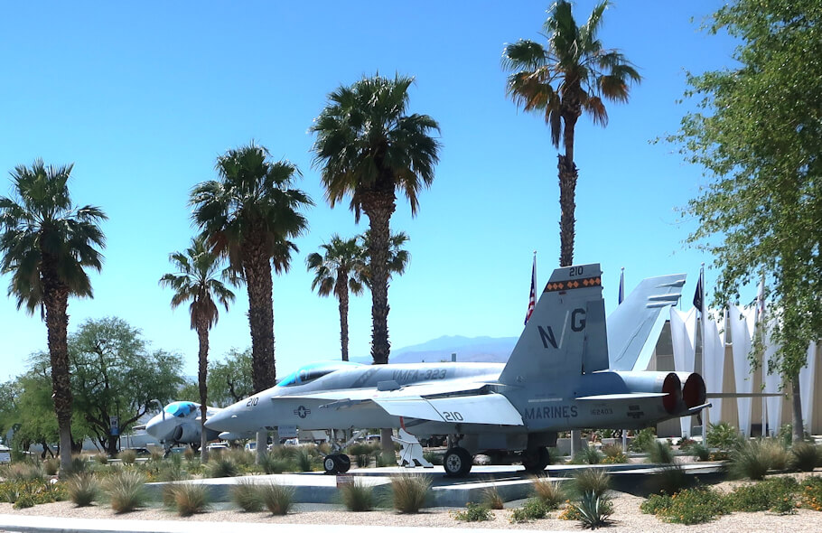 The image shows a military jet fighter, specifically a U.S. Marines F/A-18 Hornet, on outdoor display at an air museum.