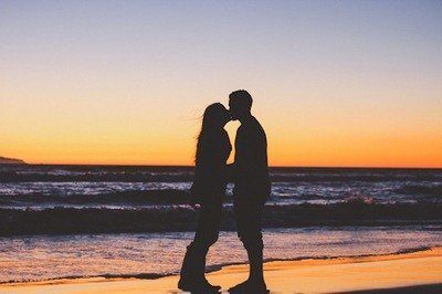 Silhouette of two lovers kissing on a beach at sunset.