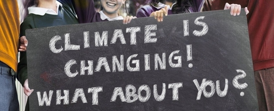 School children hold up a chalkboard with the words; Climate is changing! What about you?