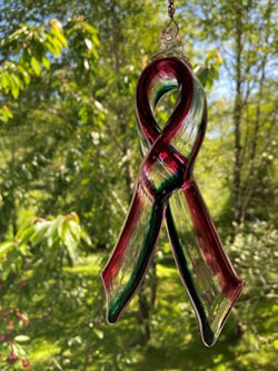 ThornMeadow Glassworks LLC submitted two images of a glass made COVID-19 Frontline Worker Solidarity Ribbon. The colors are Darkest Lagoon and Fuchsia separated by a Clear space between them. The arrangement of the Lagoon and Fuchsia represent the social distancing we are all experiencing now. The Clear that separates the colors represents all those Essential workers who hold us together.