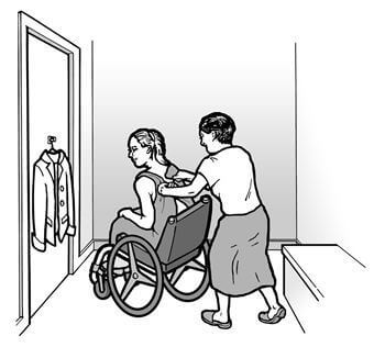 A woman using a wheelchair is trying on clothes in a dressing room and a friend is helping her.