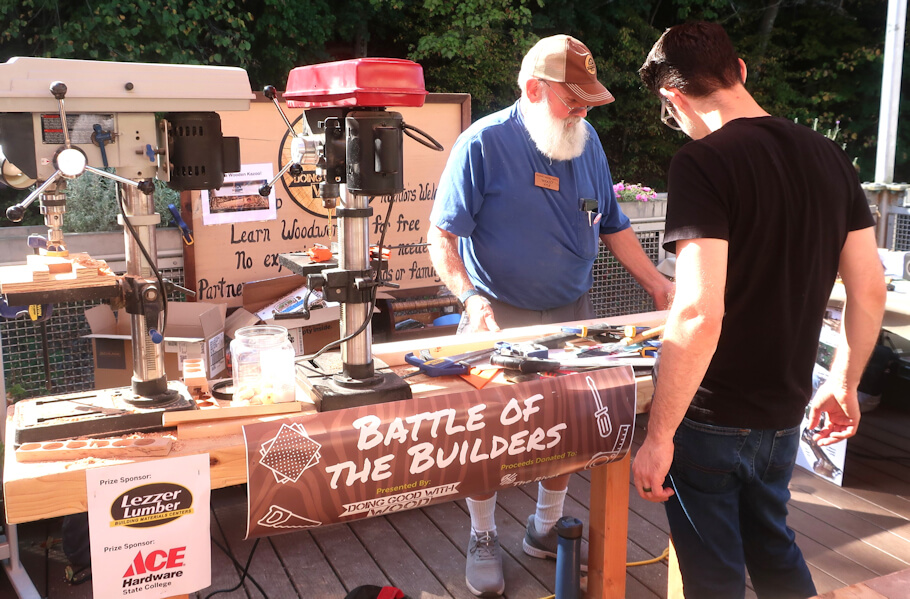 This outdoor photograph shows a woodworking demonstration booth at what appears to be a community event or fair.