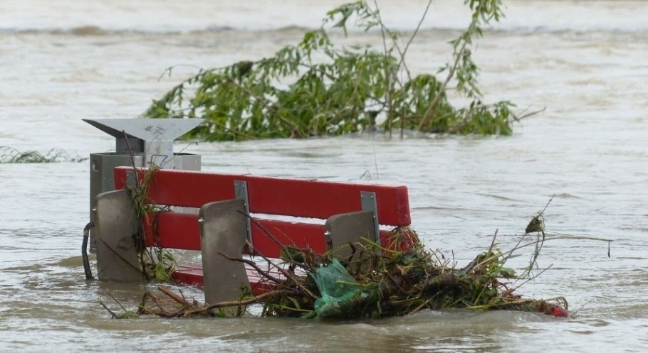 Red park bench nearly submerged by flood waters.