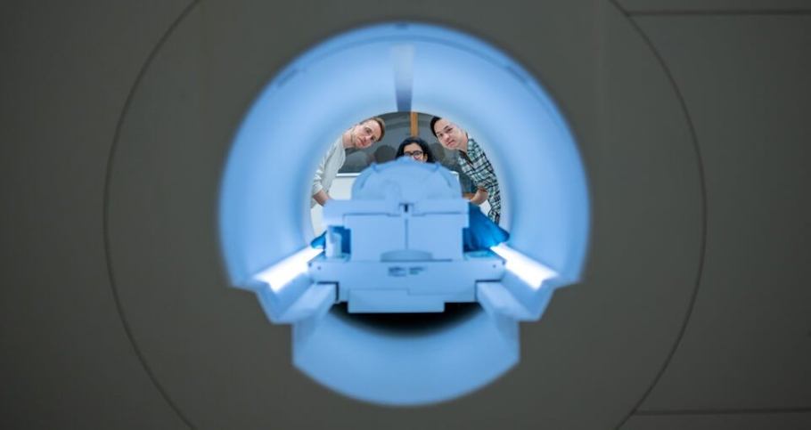 Researchers Alex Huth (left), Jerry Tang (right) and Shailee Jain (center) prepare to collect brain activity data in the Biomedical Imaging Center at The University of Texas at Austin. The researchers trained their semantic decoder on dozens of hours of brain activity data from members of the lab, collected in an fMRI scanner - Image Credit: Nolan Zunk - University of Texas at Austin.