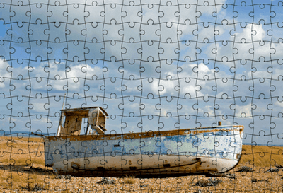 Jigsaw puzzle featuring a fishing boat high and dry on shore at low tide.