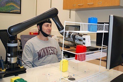 Research subjects at the University of Minnesota fitted with a specialized noninvasive brain cap were able to move the robotic arm just by imagining moving their own arms. Photo Credit: College of Science and Engineering