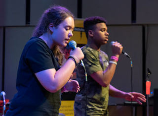 DaDaFest Scratch Performance photo of teen girl and boy singing into microphones.