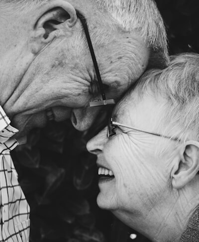 Elderly man and woman touch foreheads in black and white photo