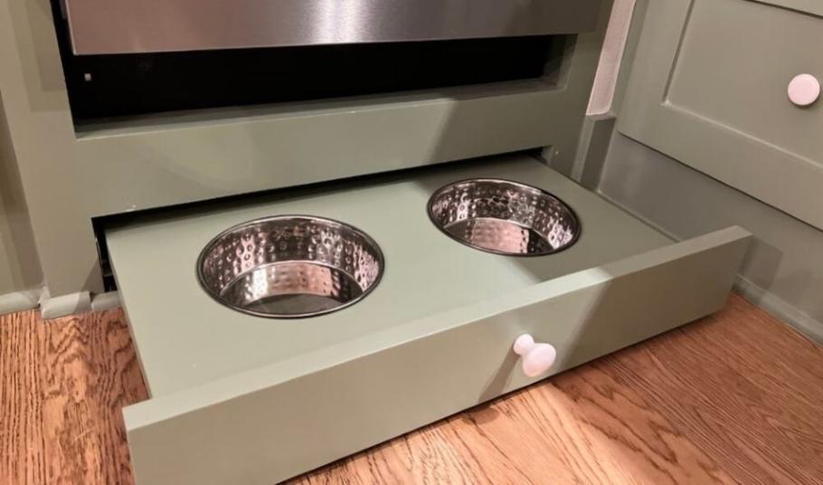 Accessible floor-level pull-out drawer with built-in water and food station bowls for service animals.