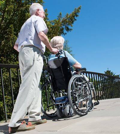 Man pushing woman in wheelchair fitted with Wheelchair Powerpack PLUS