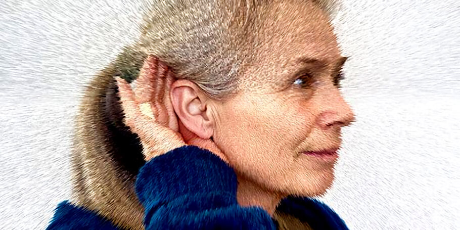 An older woman is shown in profile from the shoulders up, facing toward the right side of the image. She has light gray hair pulled back from her face, and she wears a deep blue sweater. Her right hand is raised and cupped behind her ear in the classic gesture of someone straining to listen closely, as if trying to catch a faint or distant sound.