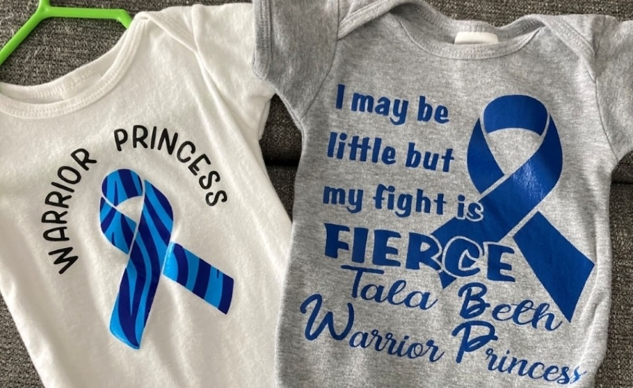 Walker-Warburg Syndrome Awareness Ribbon designs printed on two onesies. One design features a light and dark blue striped ribbon with the words - Warrior Princess. The other features a dark blue awareness ribbon with the words - I may be little but my fight is FIERCE, Tala Beth Warrior Princess.